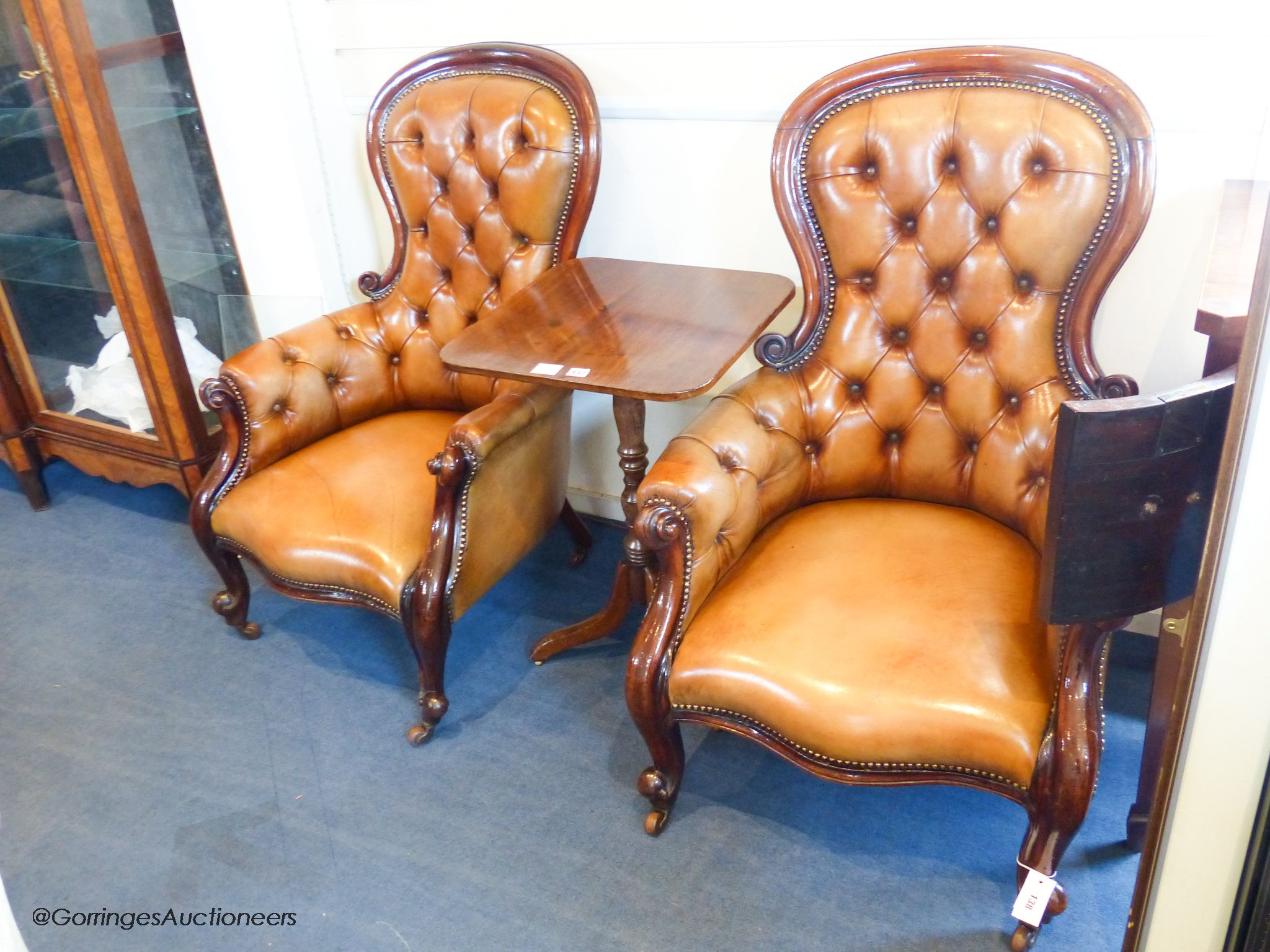 A pair of Victorian walnut and tan leather spoonback armchairs